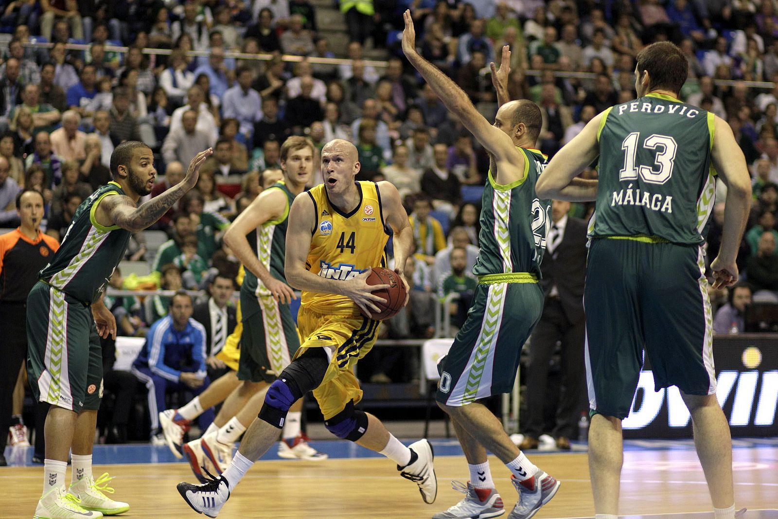 El pívot estadounidense del Alba Berlín, Zach Morley (c) entra a canasta ante los jugadores del Unicaja.