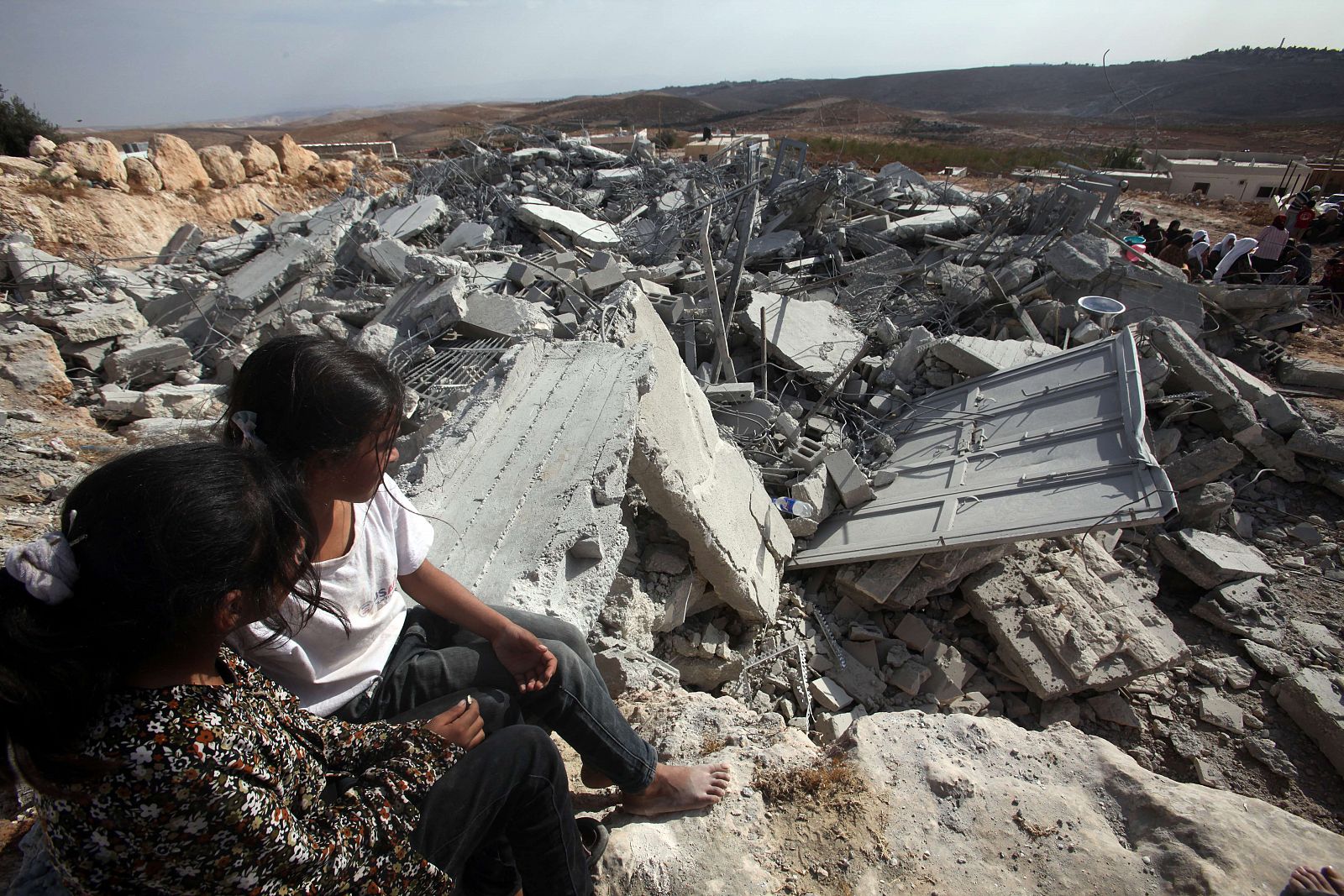 Niñas palestinas miran sus casas demoliadas por Israel al sur de la ciudad de Hebrón, en Cisjordania