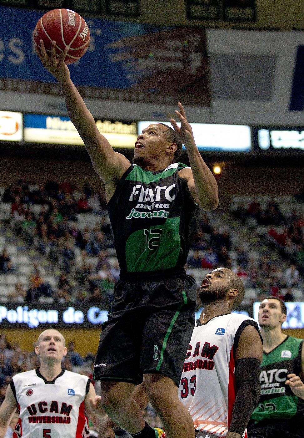 El base estadounidense del FIATC Joventut Corey Fisher (c), entra a canasta.