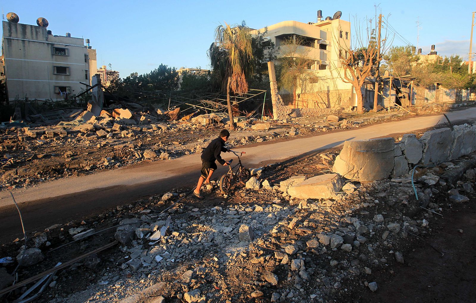 Un niño palestino empuja su bicicleta en un barrio arrasado por los bombardeos.