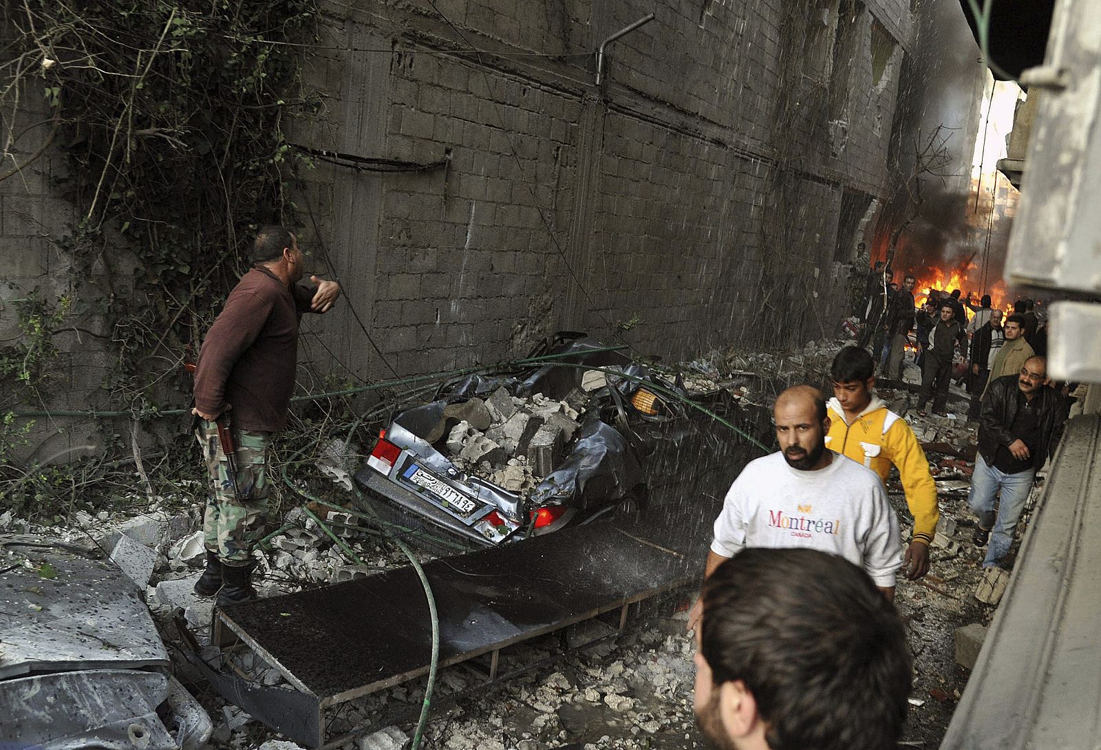 Imagen distribuida por la agencia de noticias siria SANA que muestra a un grupo de sirios observando el escenario de un ataque con coche bomba en Yarmana, de mayoría drusa, en Damasco