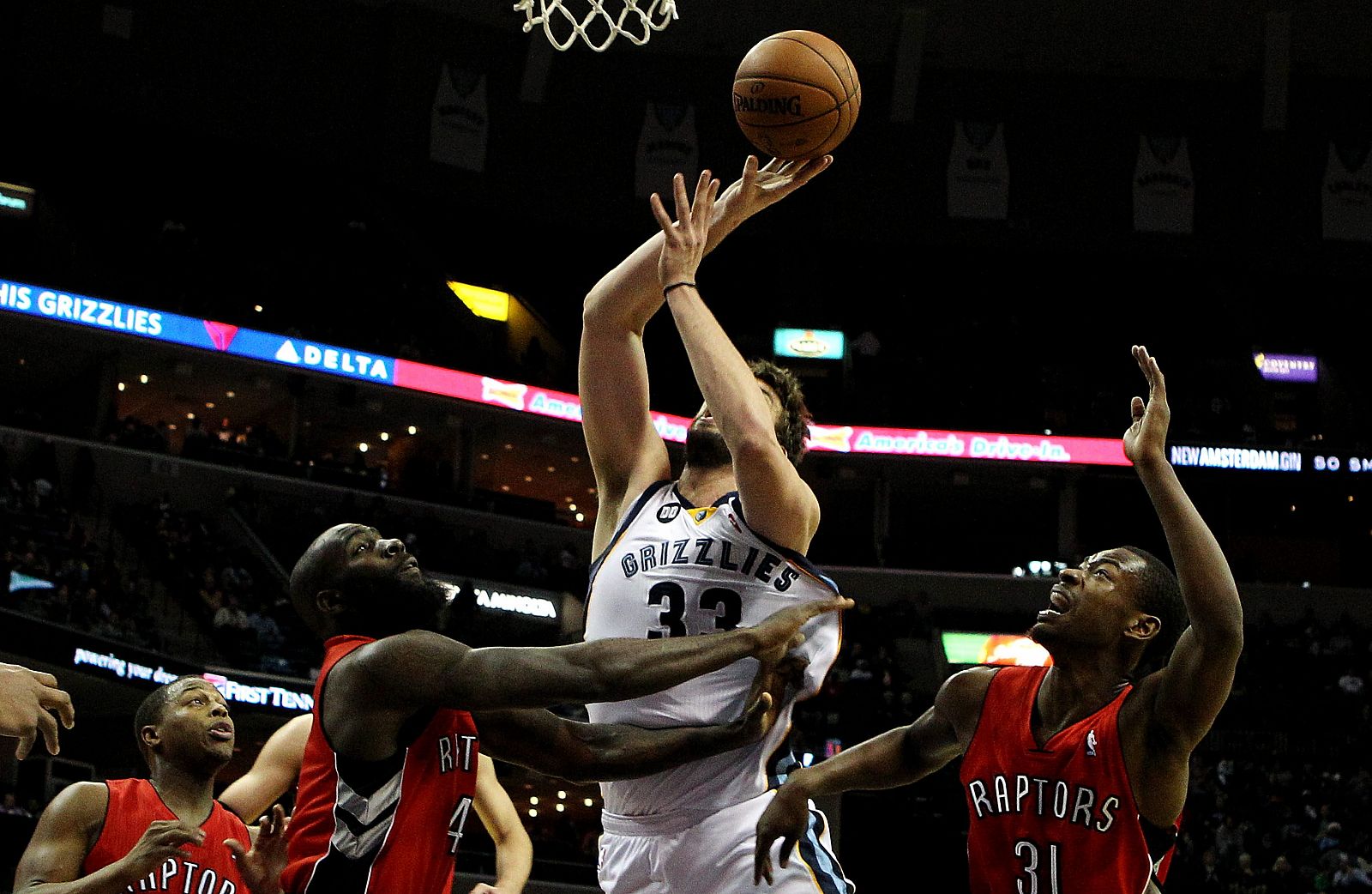 Los jugadores de los Raptors Quincy Acy (i) y Terrence Ross (d) disputan el balón con Marc Gasol.