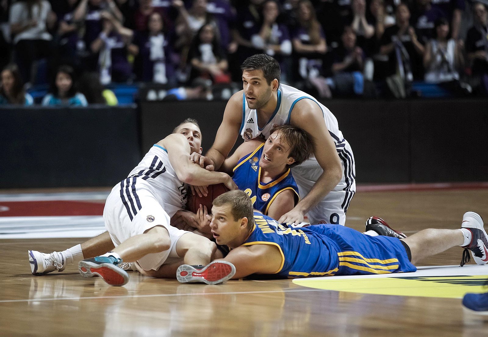 Los jugadores del Real Madrid Felipe Reyes (arriba) y Jayce Carroll (i) en lucha por el balón