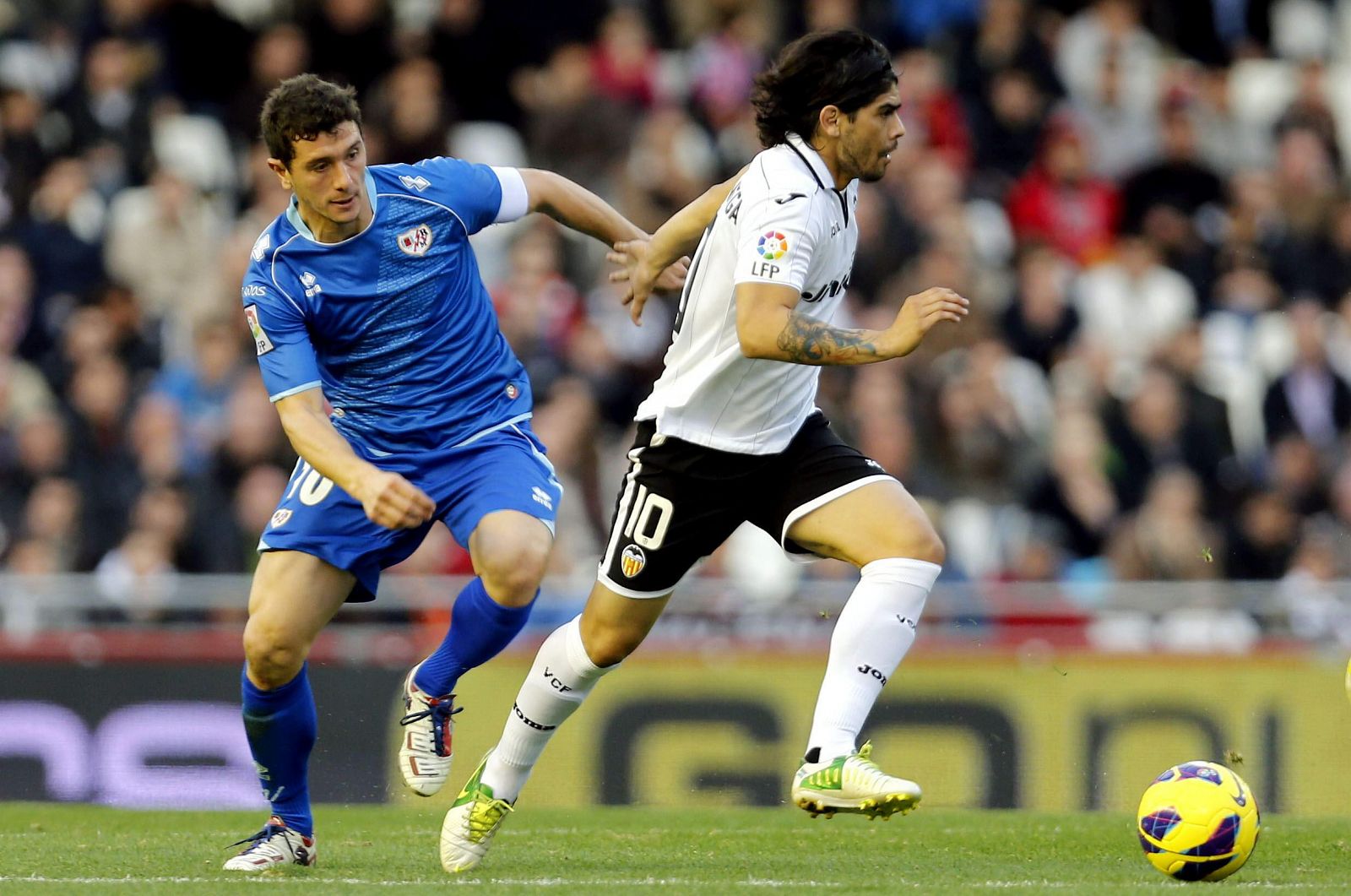 El centrocampista argentino del Valencia Ever Banega controla el balón ante el delantero del Rayo Vallecano Francisco Medina 'Piti'.