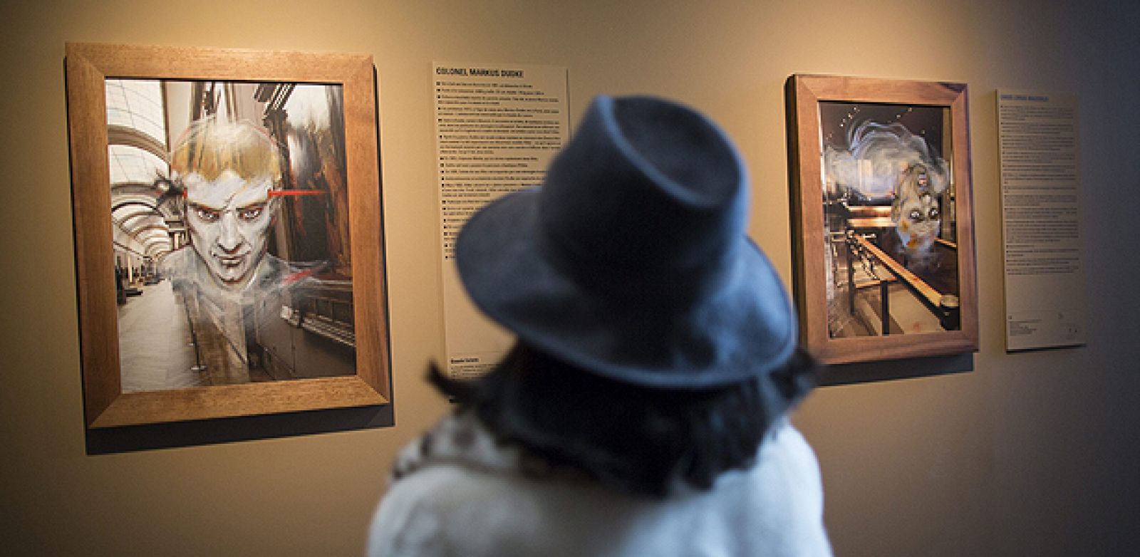 Una mujer observa los dibujos titulados "Markus Dudke" (i) y "Caius Livius Maximus" (d), del artista de cómic francés Enki Bilal, en la exposición "Los fantasmas del Louvre"