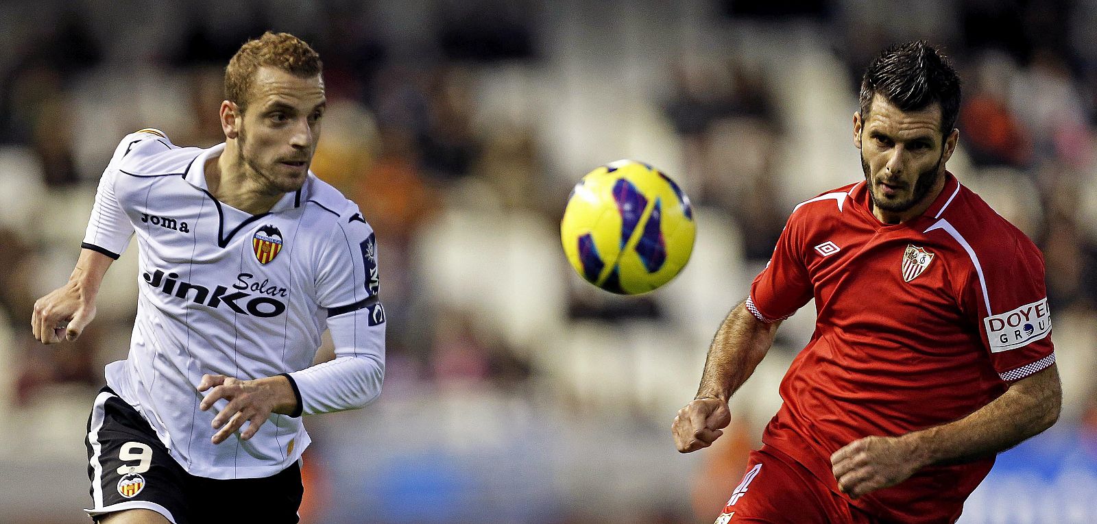 El delantero del Valencia Roberto Soldado (i) persigue un balón junto al bosnio Emir Spahic (d), del Sevilla