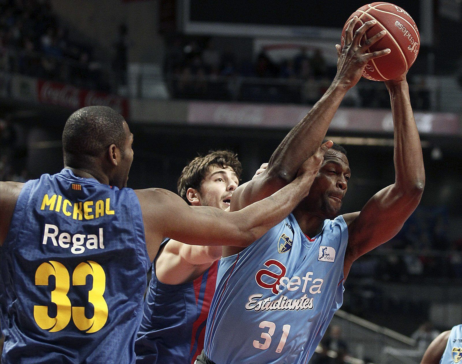 El pívot estadounidense del Asefa Estudiantes Lamont Barnes (d) se hace con la pelota ante la presión de su compatriota, el alero Pete Mickeal del Barcelona Regal (i)