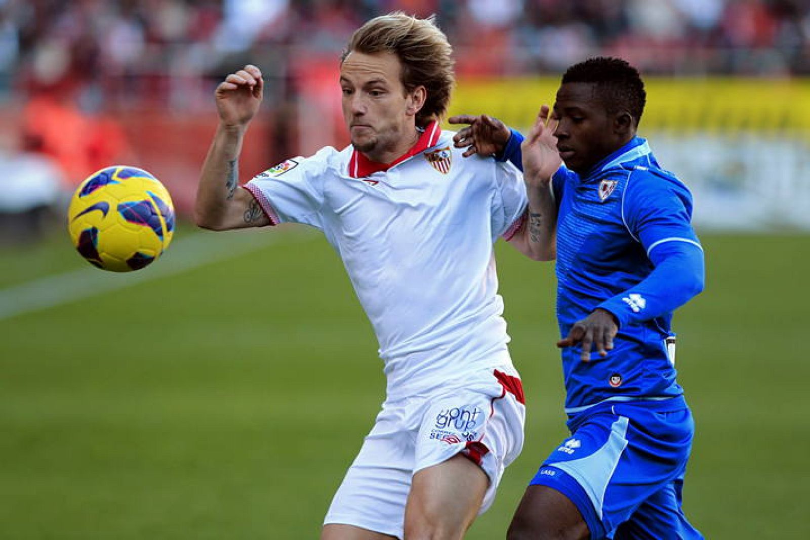 El centrocampista del Sevilla Ivan Rakitic (i) intenta el control del balón ante el delantero guineano del Rayo Vallecano Lass Bangoura (d).