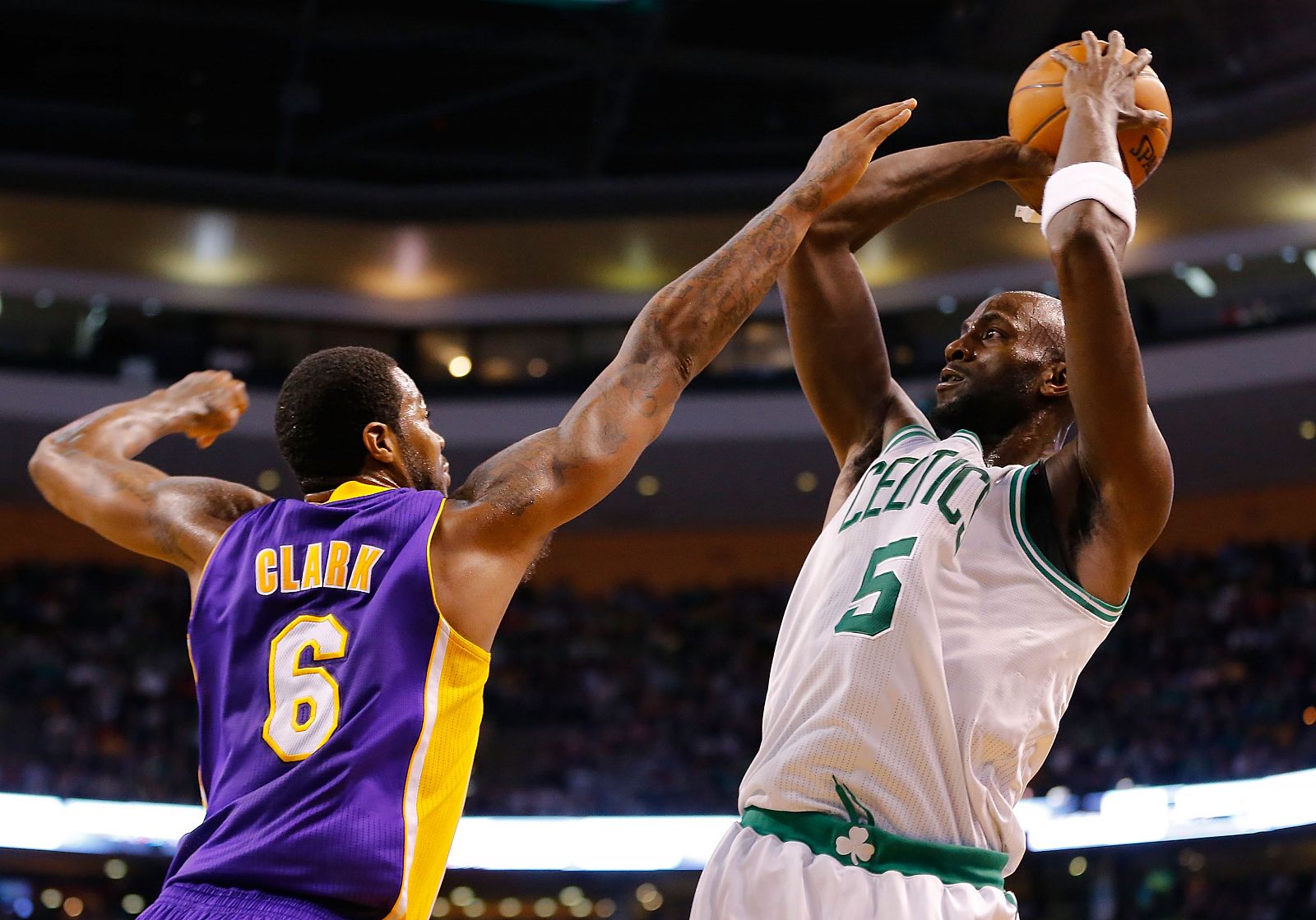 Kevin Garnett (d), de los Boston Celtics, tira a canasta tapado por Earl Clark de los Ángeles Lakers