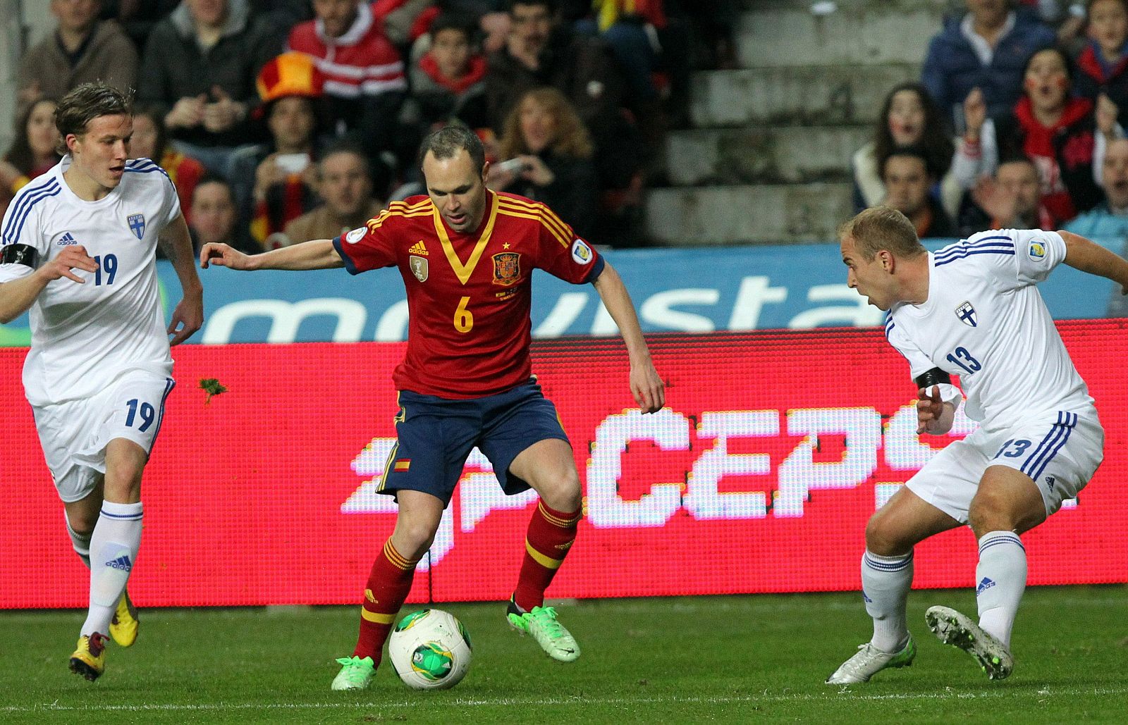 El centrocampista de la selección española Andrés Iniesta (d) controla el balón frente a los centrocampistas de la selección finlandesa