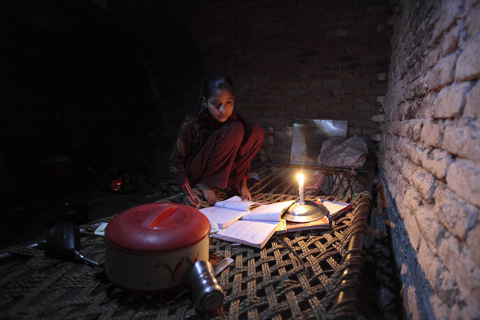 Norín, de 13 años, usa una vela para estudiar debido a un corte eléctrico en un barrio de chabolas de Islamabad