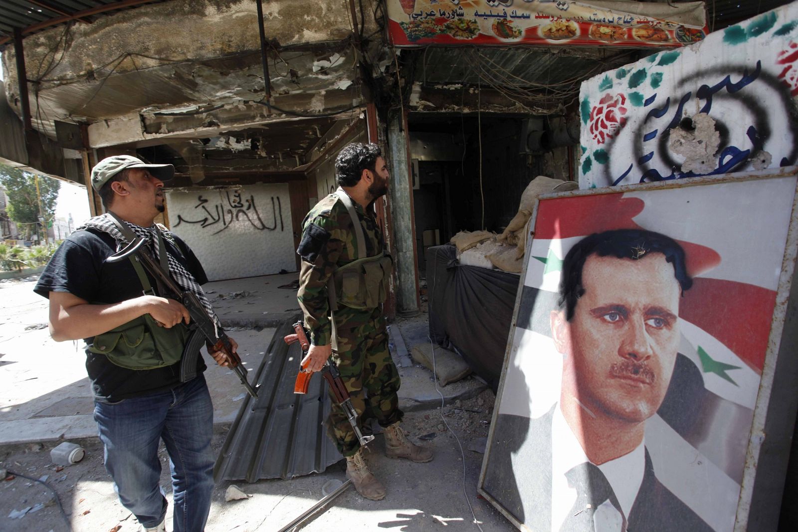 Fieles a Bachar al Asad montan guardia en Damasco junto a un retrato del presidente sirio