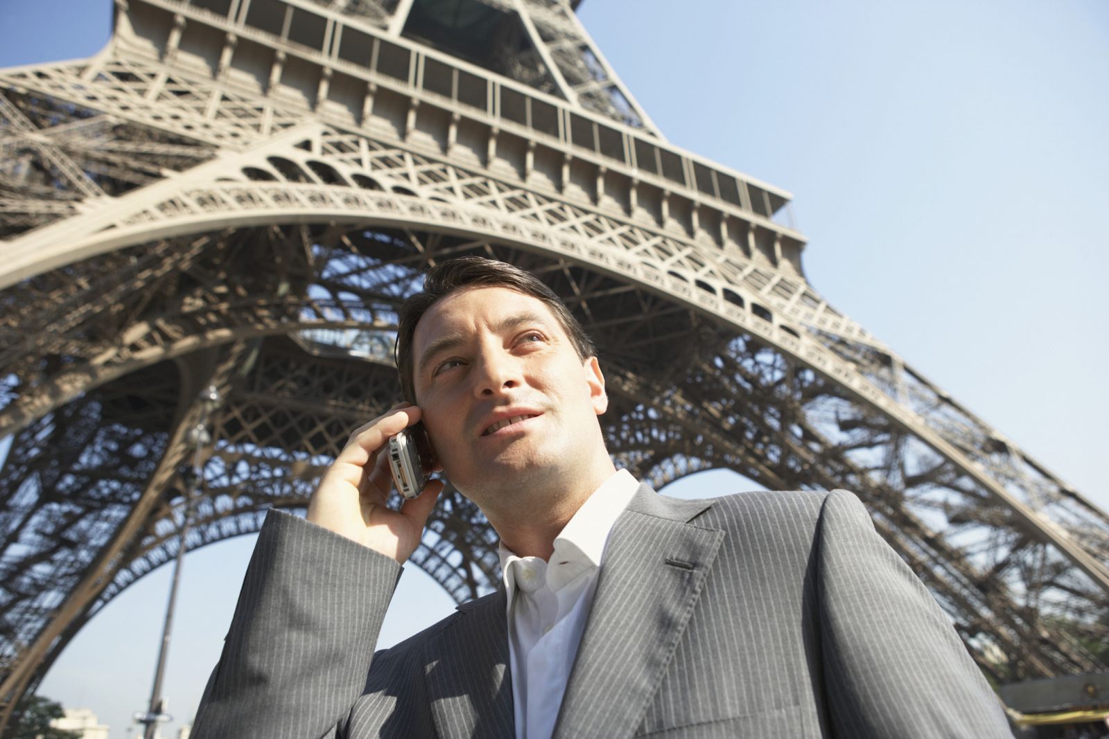 Un hombre de negocios hablando por móvil junto a la Torre Eiffel, en París.