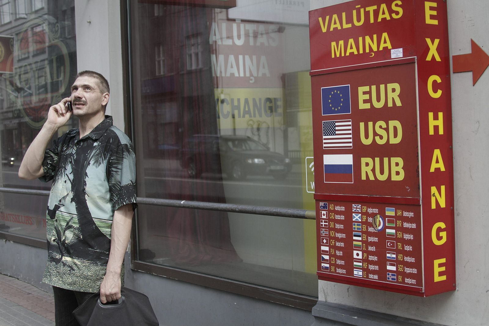 Un hombre permanece junto a una oficina de cambio de moneda en Riga
