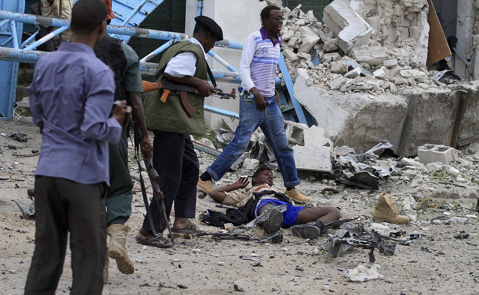 Somali government soldiers stand near injured man after suicide bomb attack inside the United Nations compound in the Somali capital Mogadishu