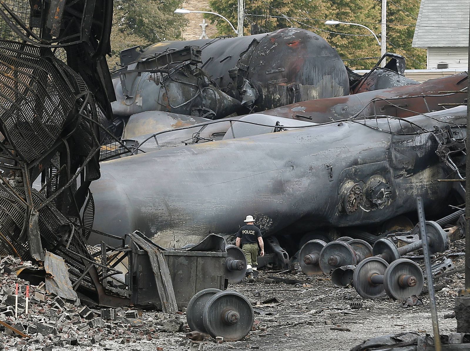 A police officer walks amongst axle gear in Lac Megantic