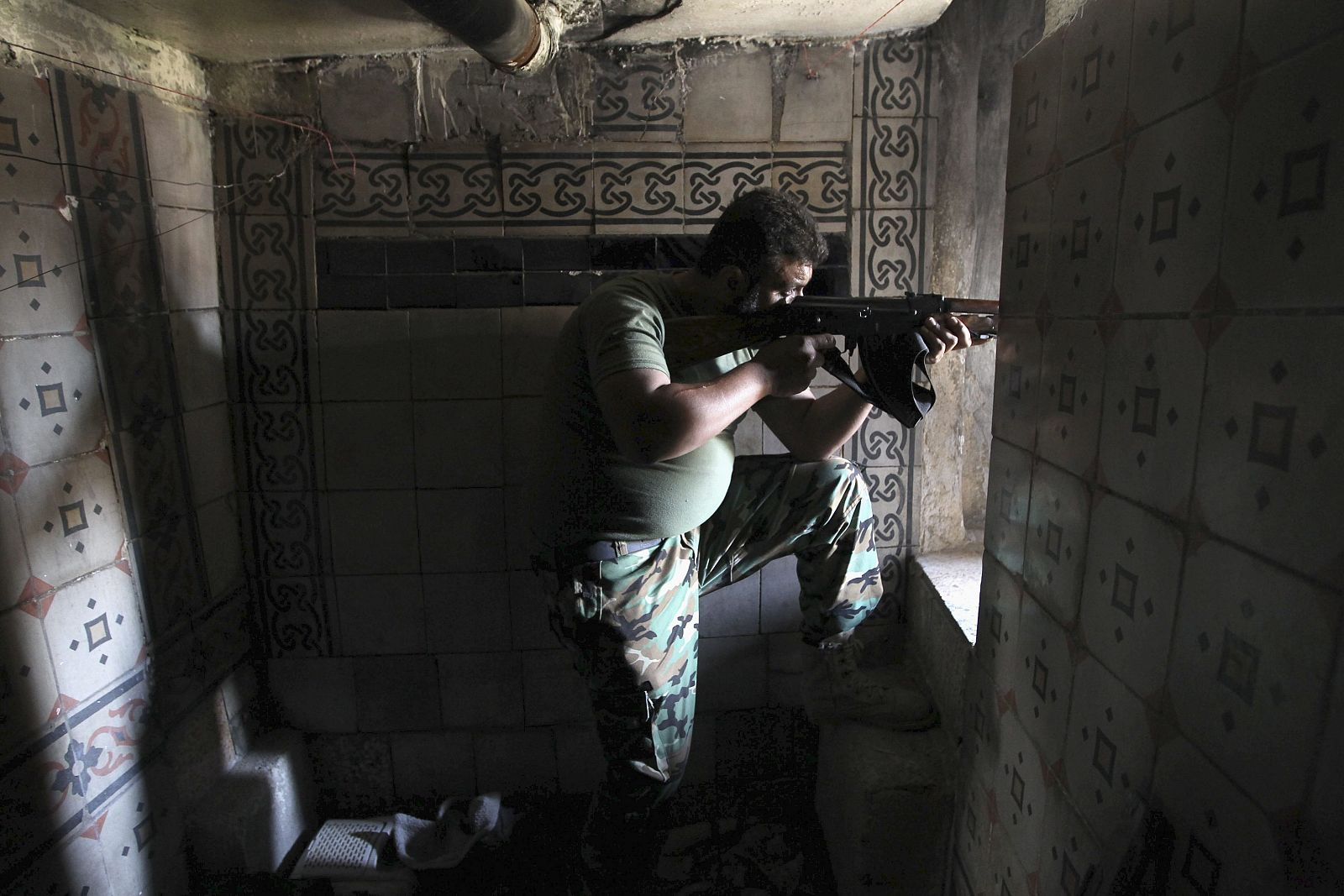 A Free Syrian Army fighter aims weapon as he takes position inside house in city of Aleppo