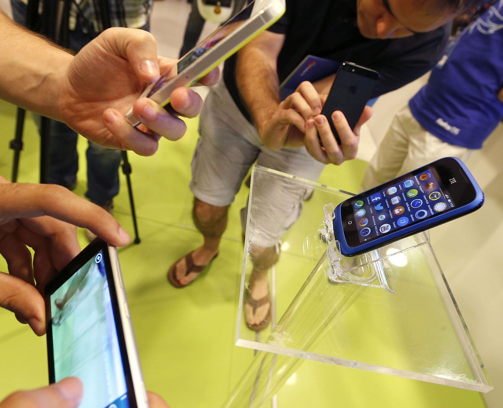 Varias personas observan en una tienda de telefonía de Madrid, el primer teléfono móvil del mundo con sistema operativo abierto Firefox OS