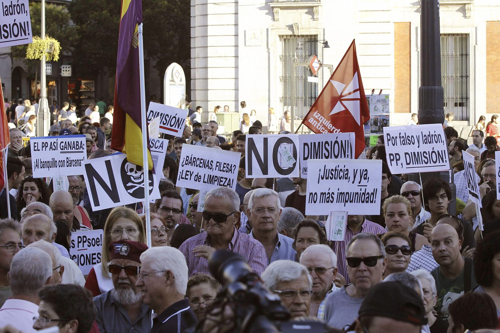 Varias personas muestran pancartas durante la concentracion organizada por IU y otras organizaciones en la Puerta del Sol, en Madrid.