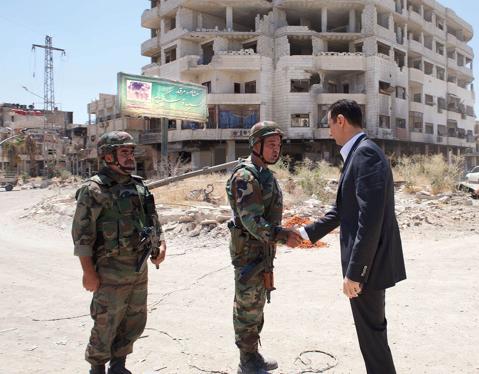 Syria's President Bashar al-Assad shakes hands with a military personnel during his visit to a military site at Darya