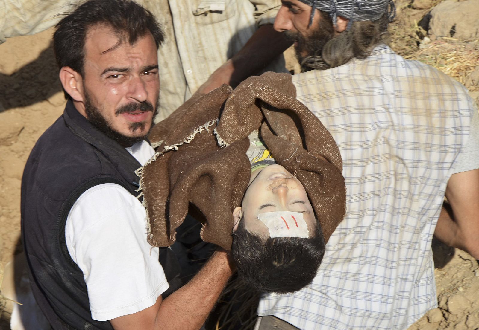 Un hombre traslada el cuerpo de una de las víctimas del supuesto ataque químico para su funeral en Hamoria, Siria.