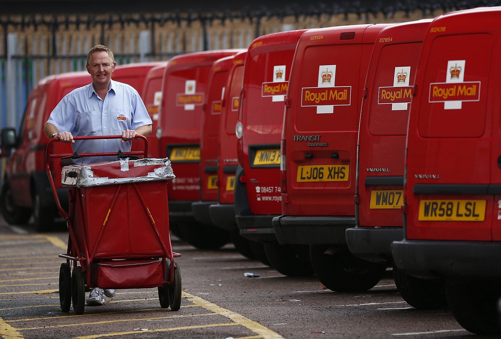 Un cartero empuja un carro con correo de Royal Mail