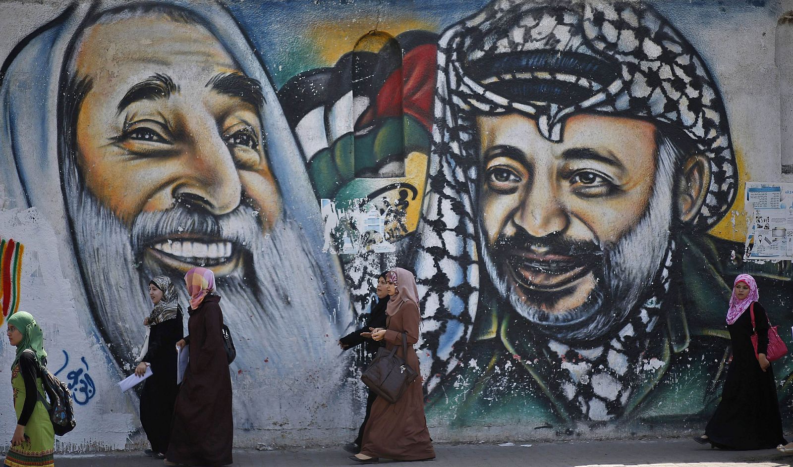 Estudiantes palestinos pasan frente a un mural en Gaza