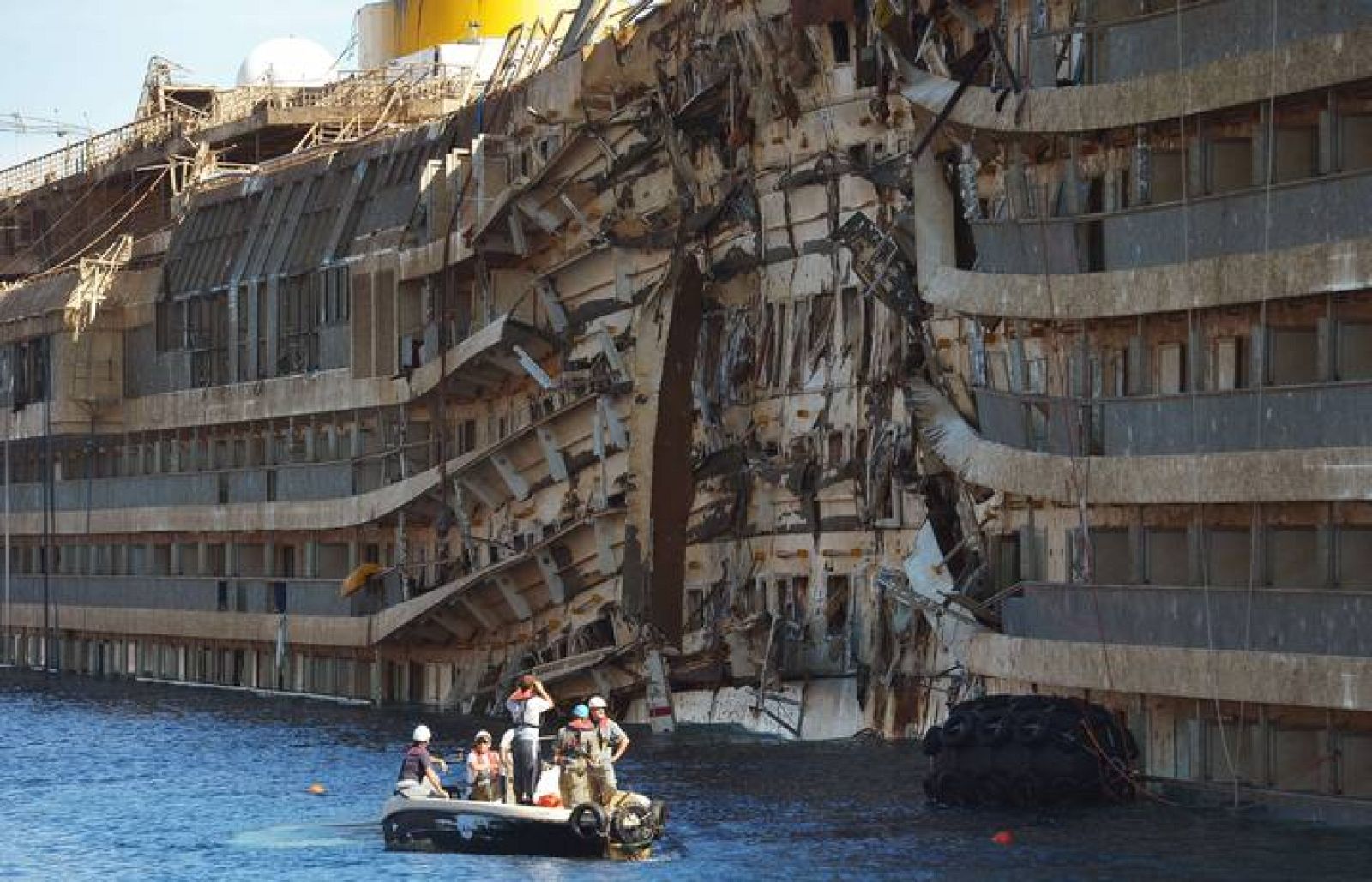 Miembros de los equipos de rescate inspeccionan el casco del 'Costa Concordia' frente a la isla de Giglio