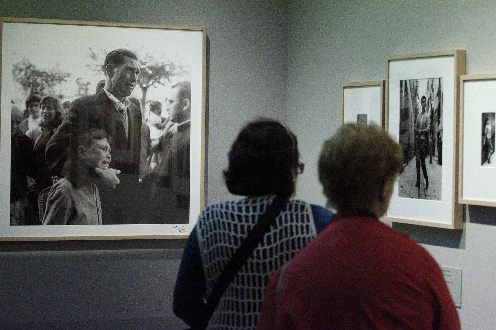 Dos mujeres contemplan una foto sobre la emigración española