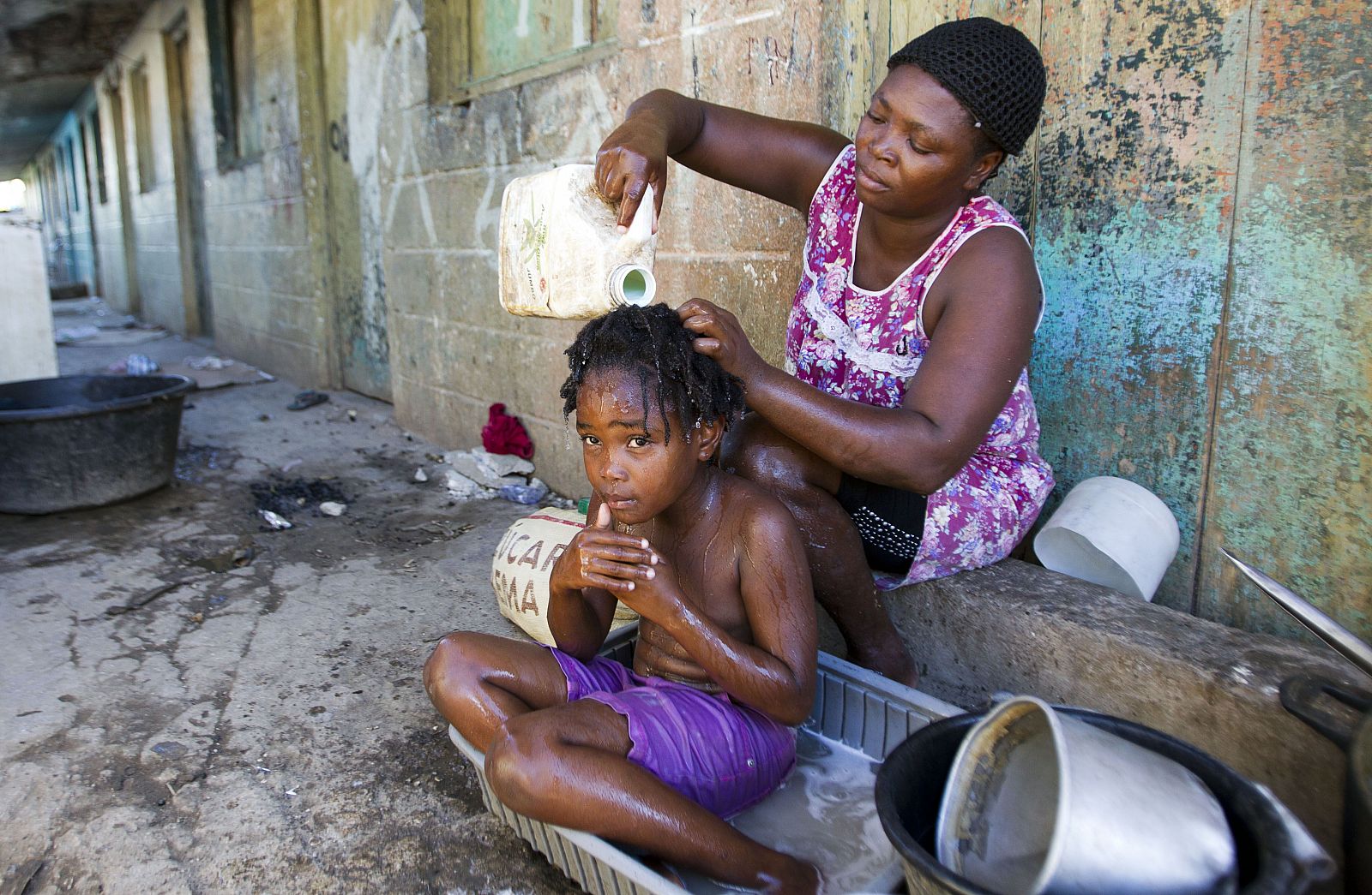 Una mujer haitiana lava el pelo a su hija