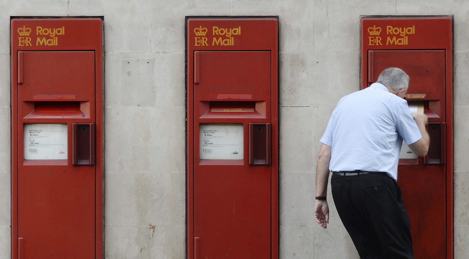 Un hombre echa una carta en un buzón de correos de una oficina del servicio Royal Mail, en Londres