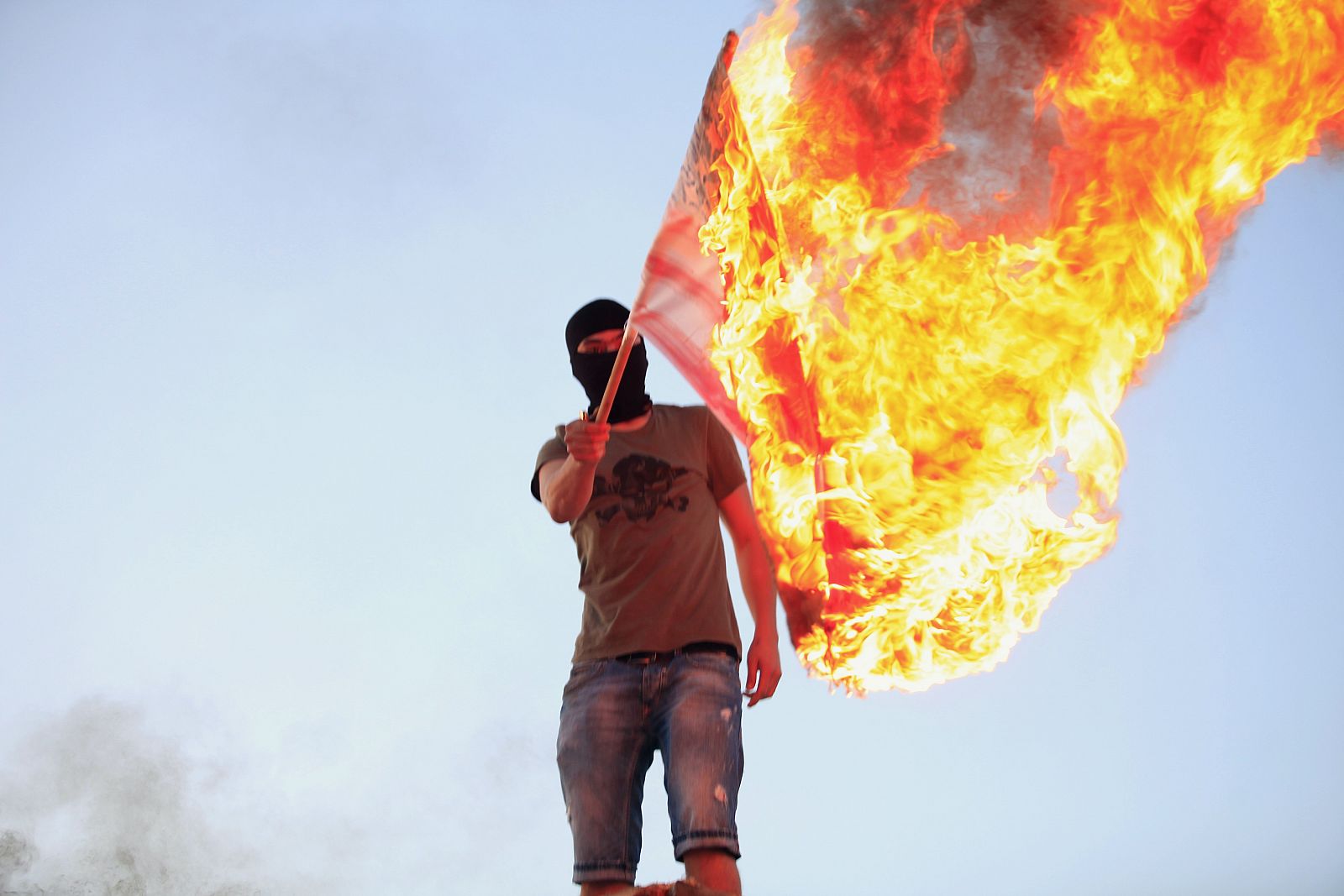 Un libio protesta quemando una bandera en Bengasi.