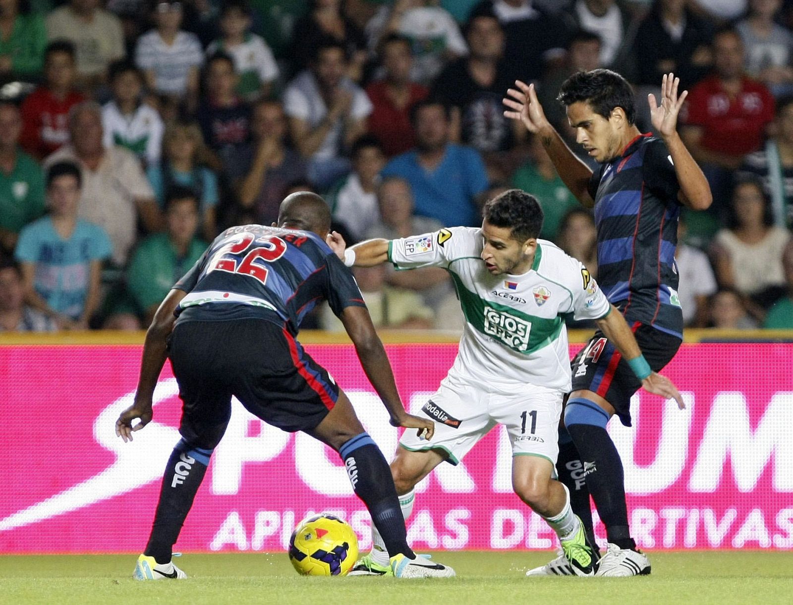 El delantero del Elche, Ferrán Corominas, intenta superar la defensa de los jugadores del Granada, el francés Dimitri Foulquier y Francisco Manuel Rico.