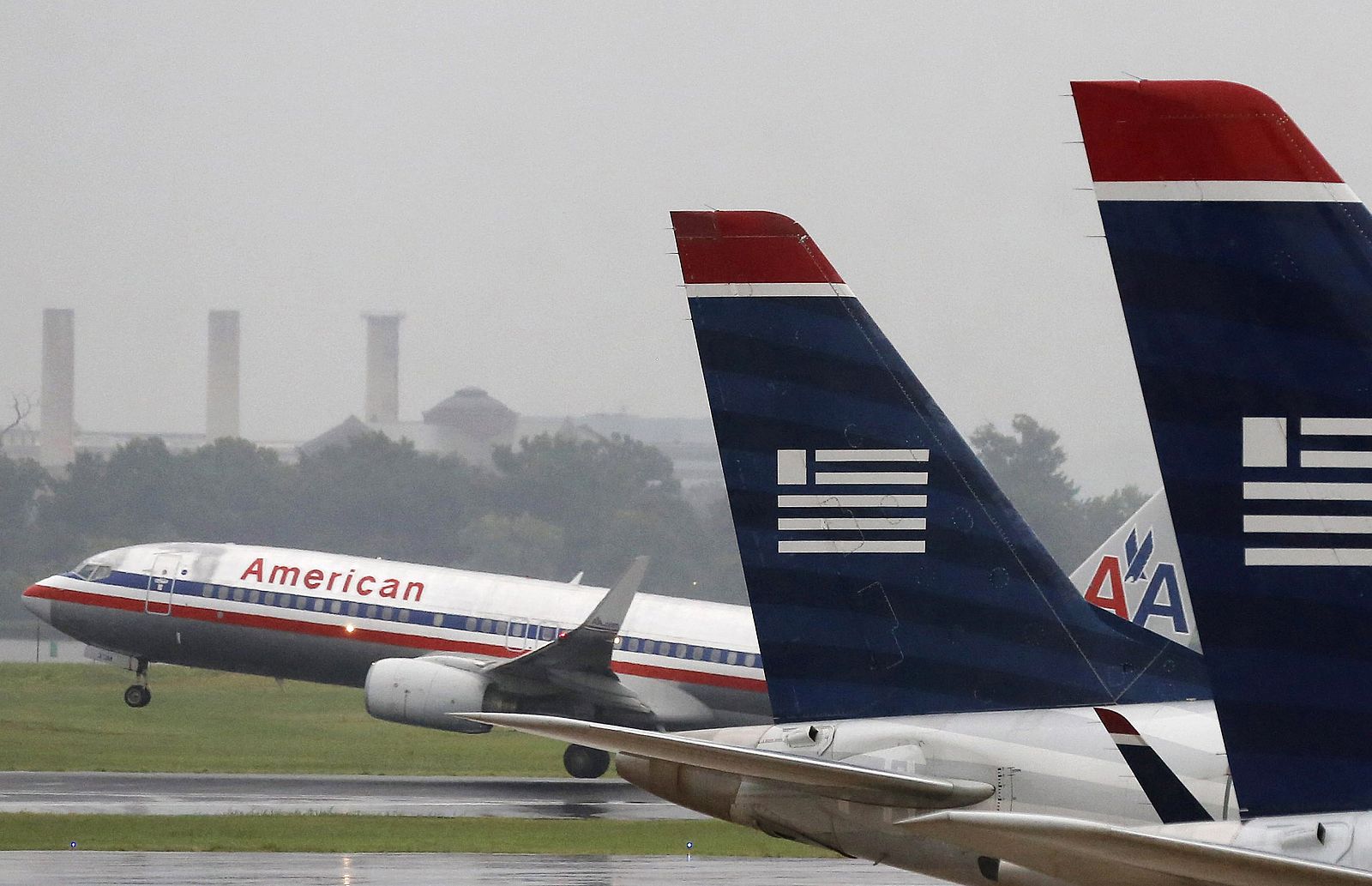Un avión de American Airlines despega mientras aeronaves de U.S. Airways se encuentran aparcadas en el Aeropuerto Reagan de Washington