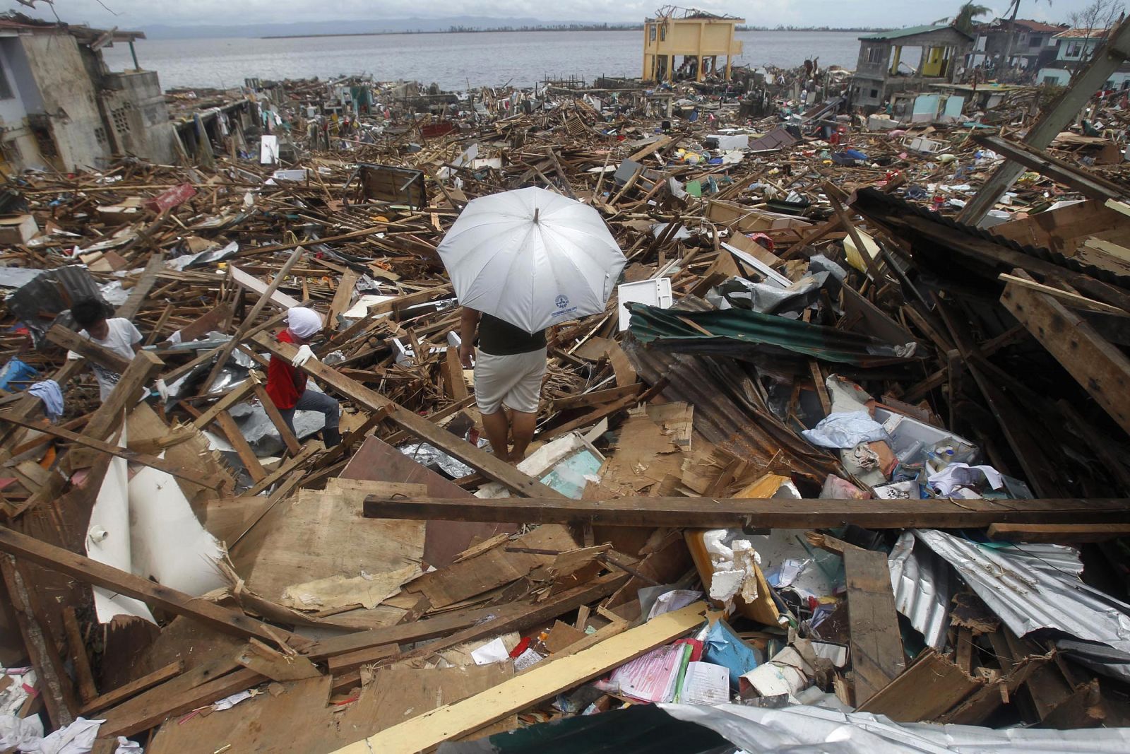 Varias personas caminan entre los escombros que ha provocado el tifón Haiyan en Filipinas