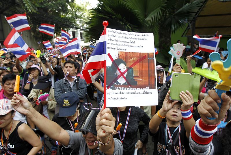 Manifestantes anti-gubernamentales en Tailandia muestran una fotografía tachada de la primera ministra, Yingluck Shinawatra