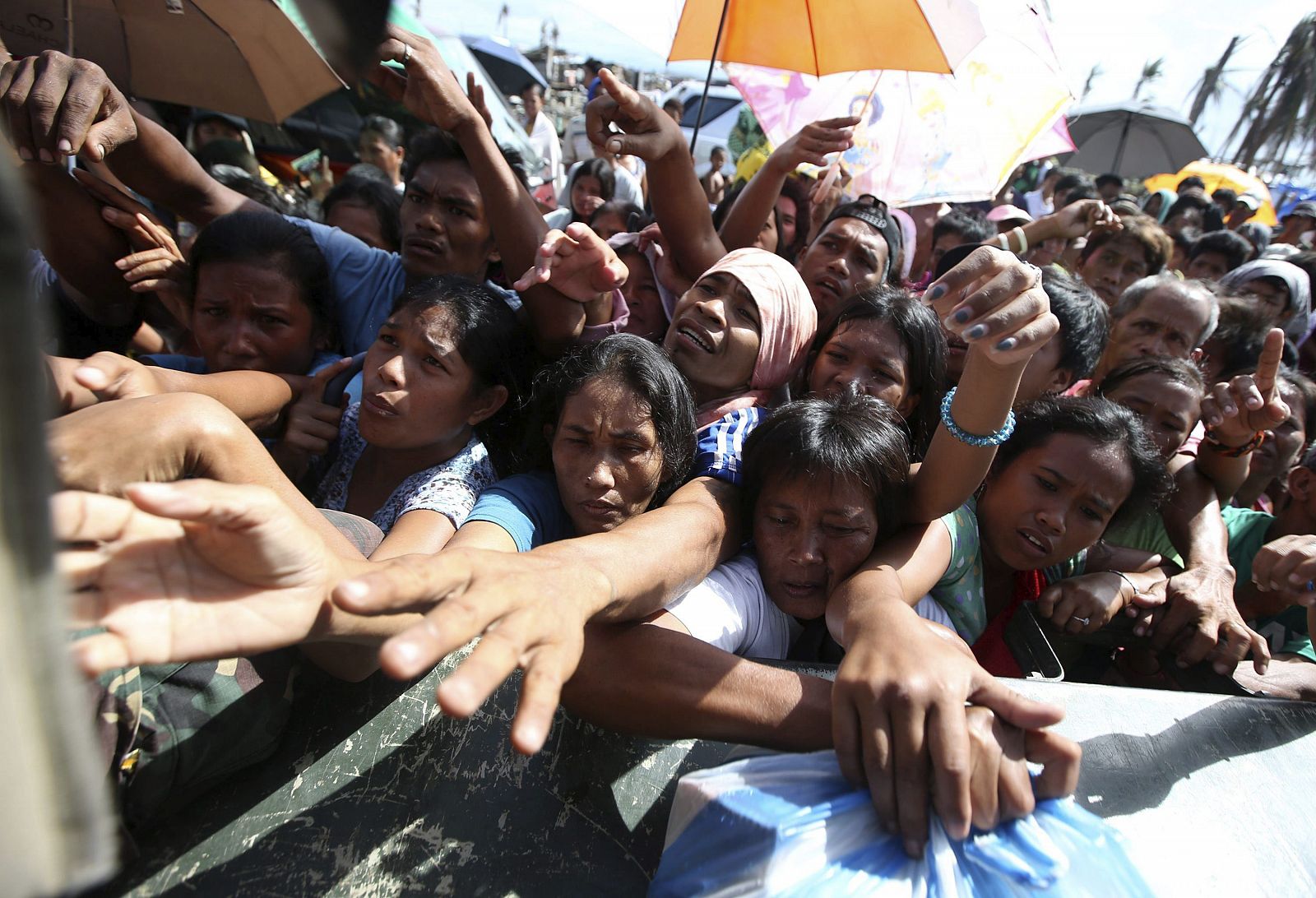 Afectados por el Tifón Haiyan se agolpan alrededor de las personas que les reparten bienes de primera necesidad en la devastada ciudad de Tacloban, en la isla de Leyte (Filipinas)