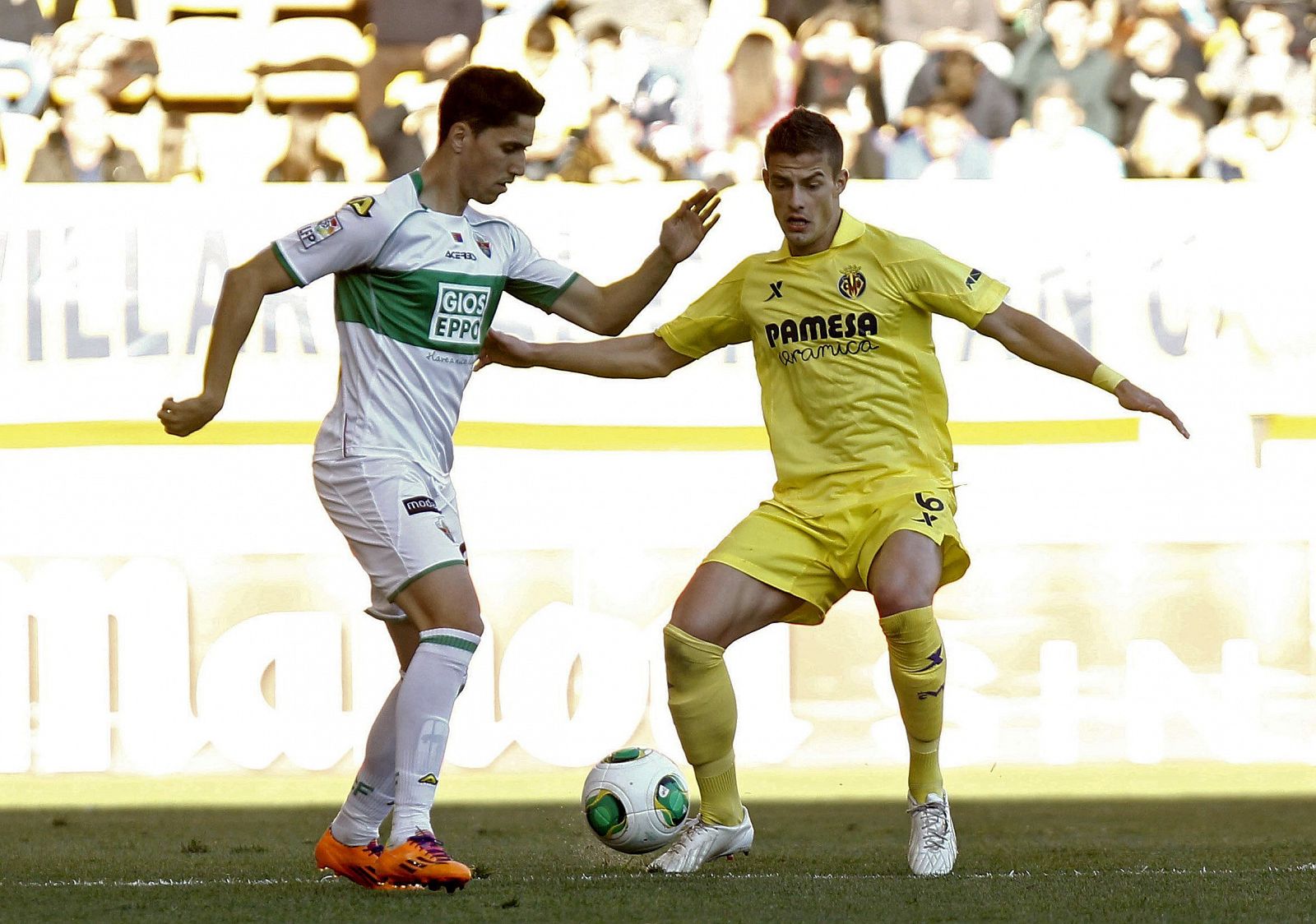 El defensa serbio del Villarreal, Aleksandar Pantic (d), pelea un balón con el delantero del Elche Carles Gil