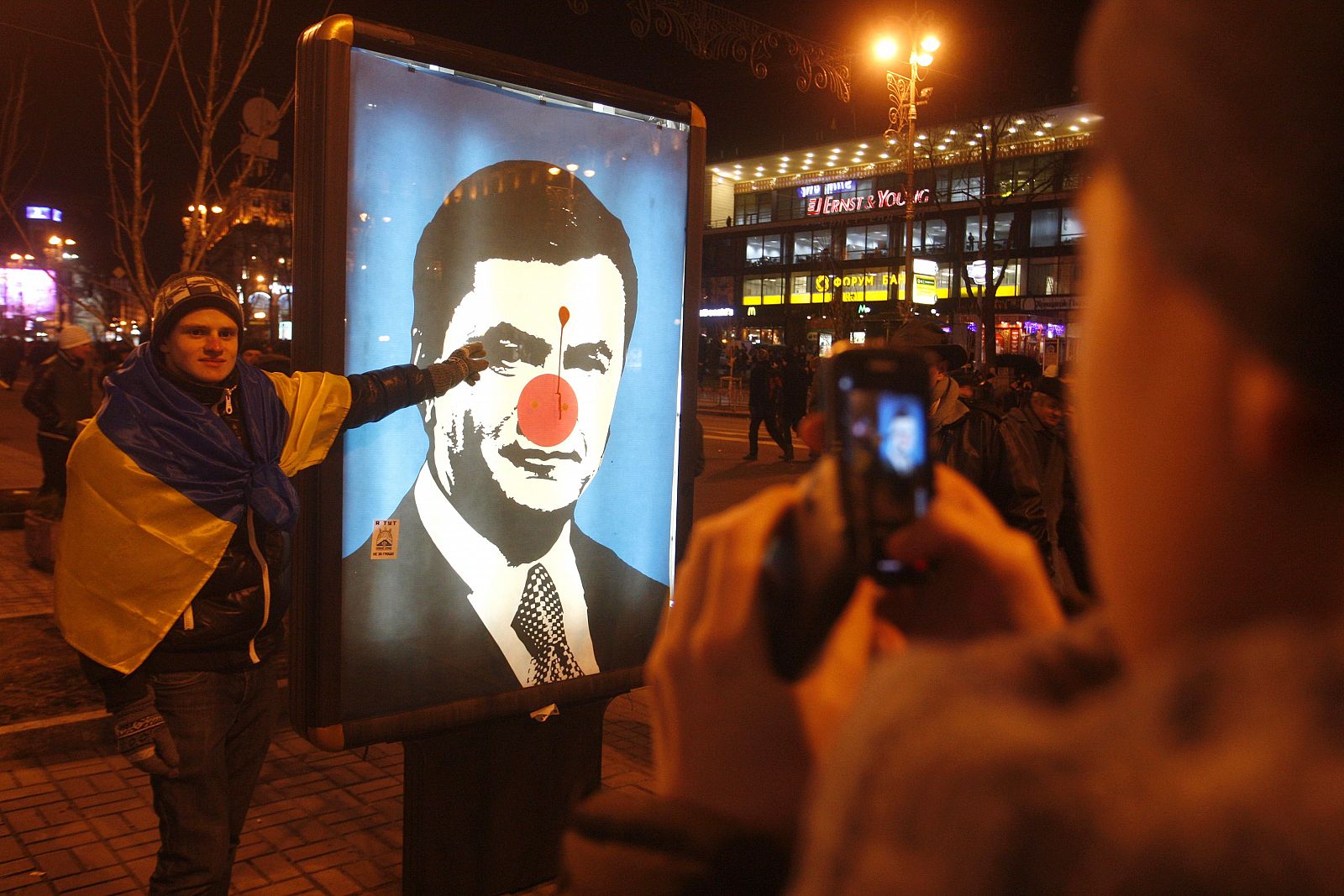 Un manifestante posa frente a una imagen sarcástica del presidente ucraniano, Víktor Yanúkovich, en Kiev