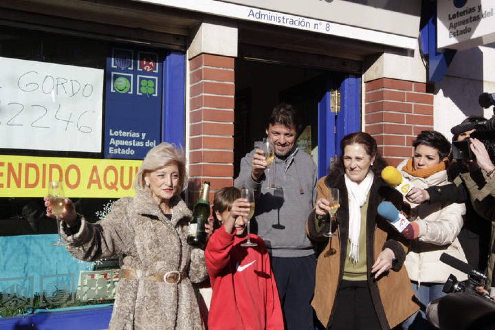 La lotera Maria Luisa celebra con una familia agraciada con el Gordo a la entrada de su administración, la número 8 de Leganés