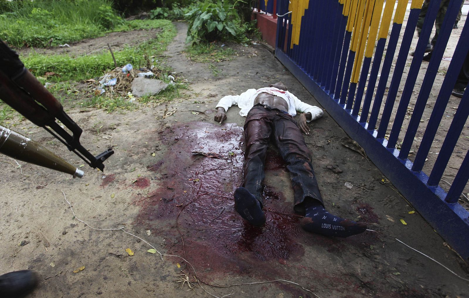 El cuerpo de un atacante sin identificar yace a las fueras de la sede de la radiotelevisión estatal en Kinshasa.