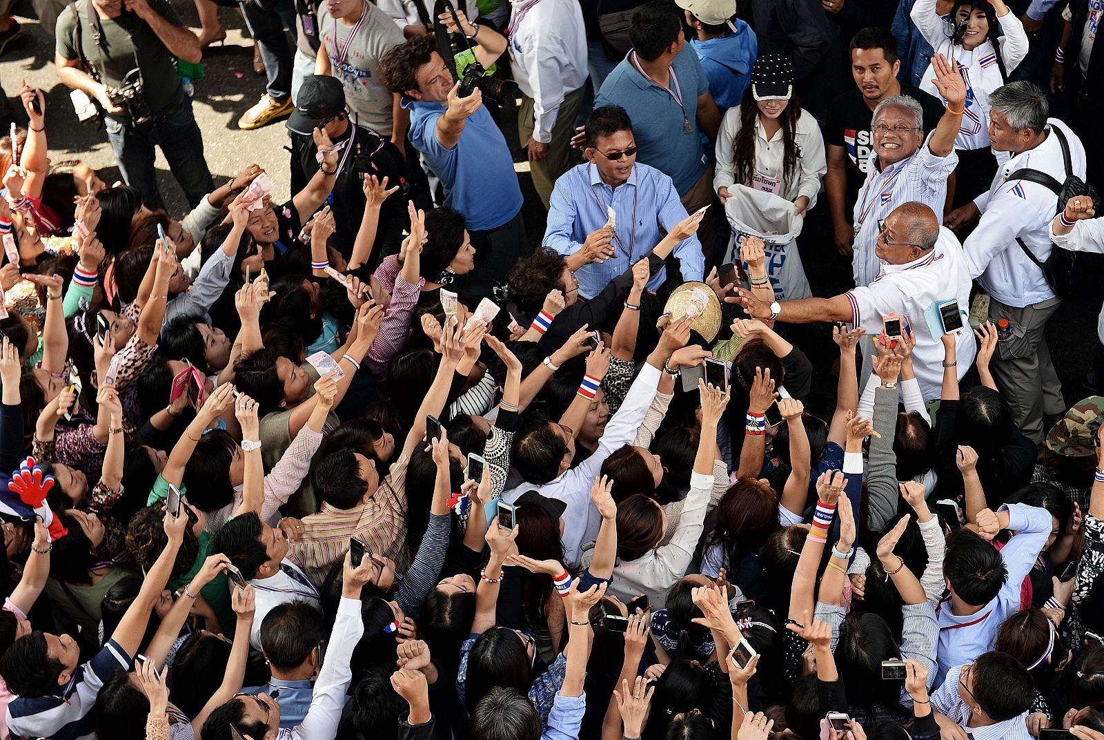 Decenas de manifestantes opositores fotografían y donan dinero al líder de las protestas, Suthep Thaugsuban, en Bangkok.