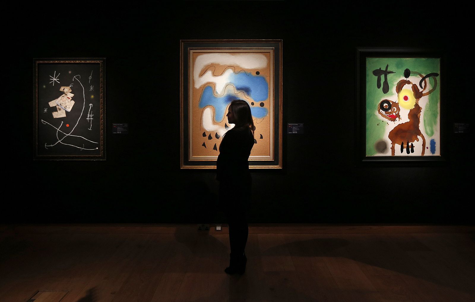 A Christie's employee poses with a selection of artworks by Joan Miro at Christie's auction house in London