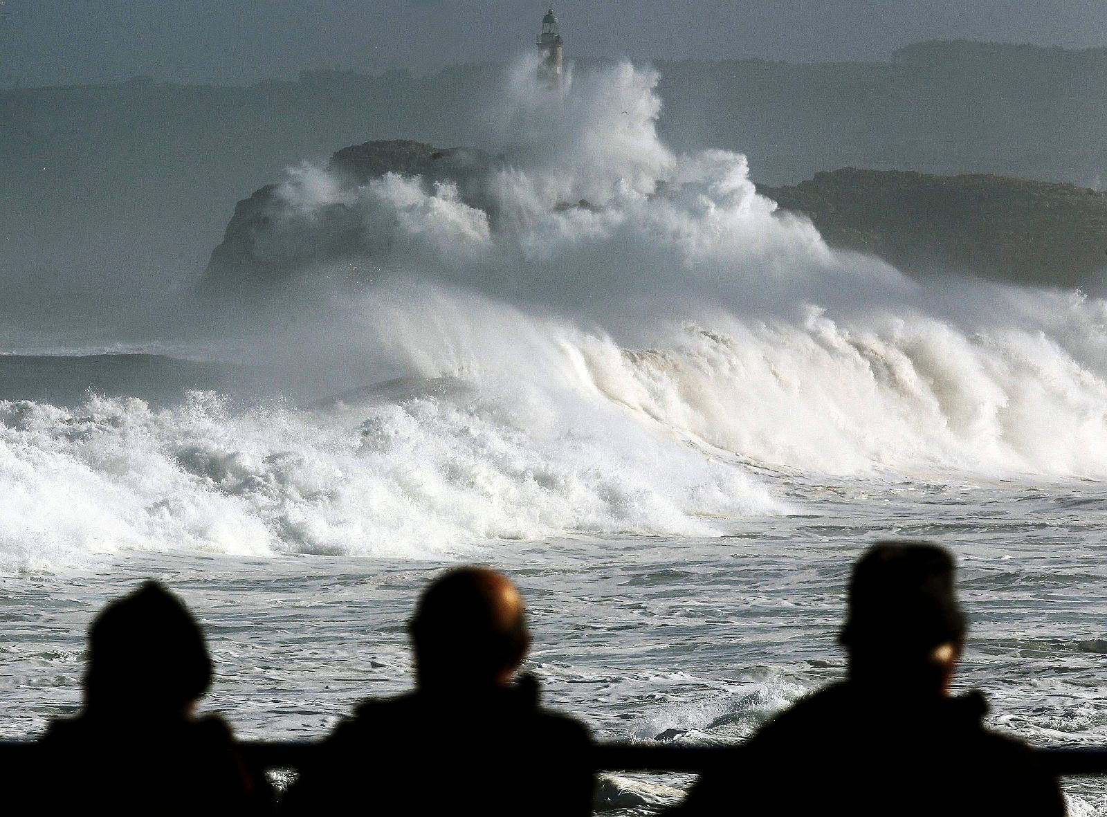 Varias personas observan la isla de Mouro batida por las olas en Santander