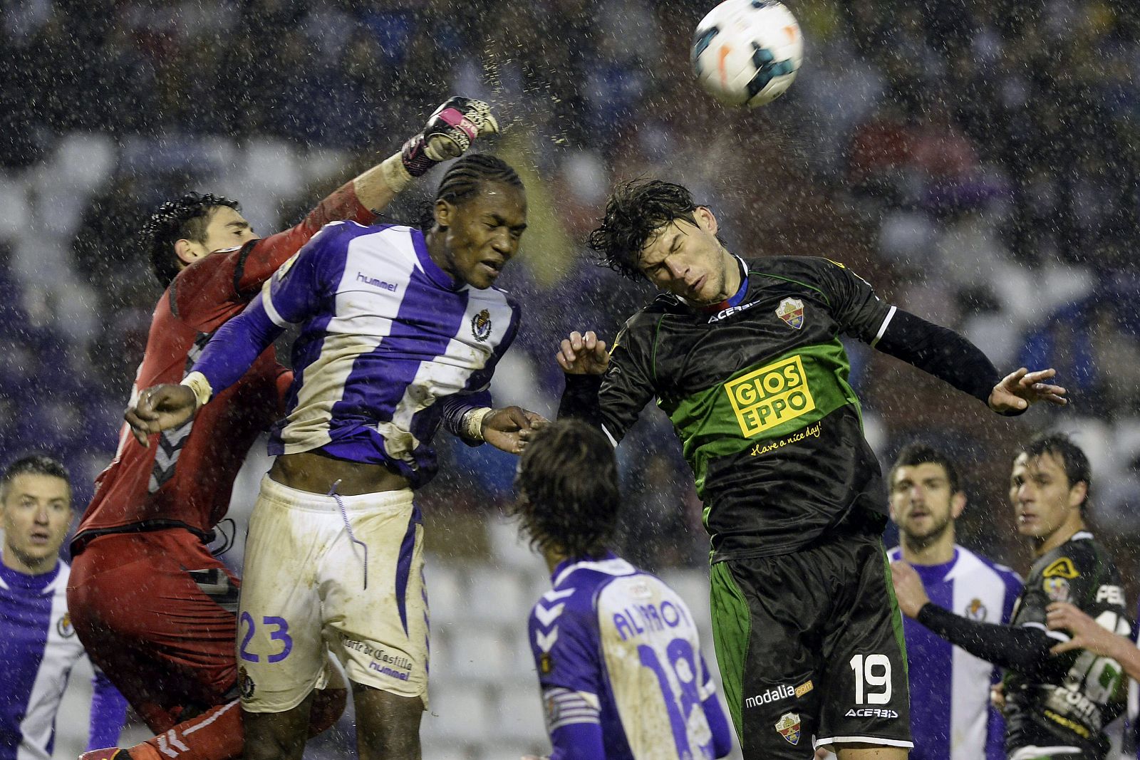 El defensa del Elche Cristian Sapunaru intenta rematar de cabeza ante los jugadores del Real Valladolid Manucho y el portero Diego Mariño.