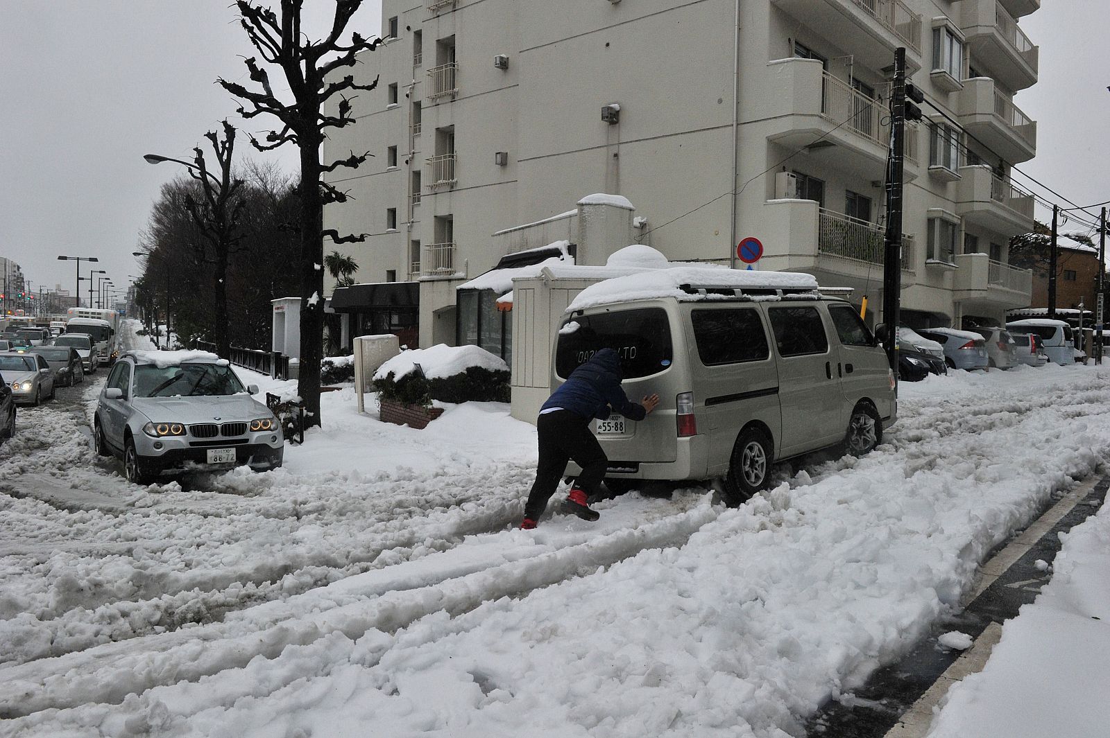 Un hombre empuja su vehículo en una carretera nevada en Tokio