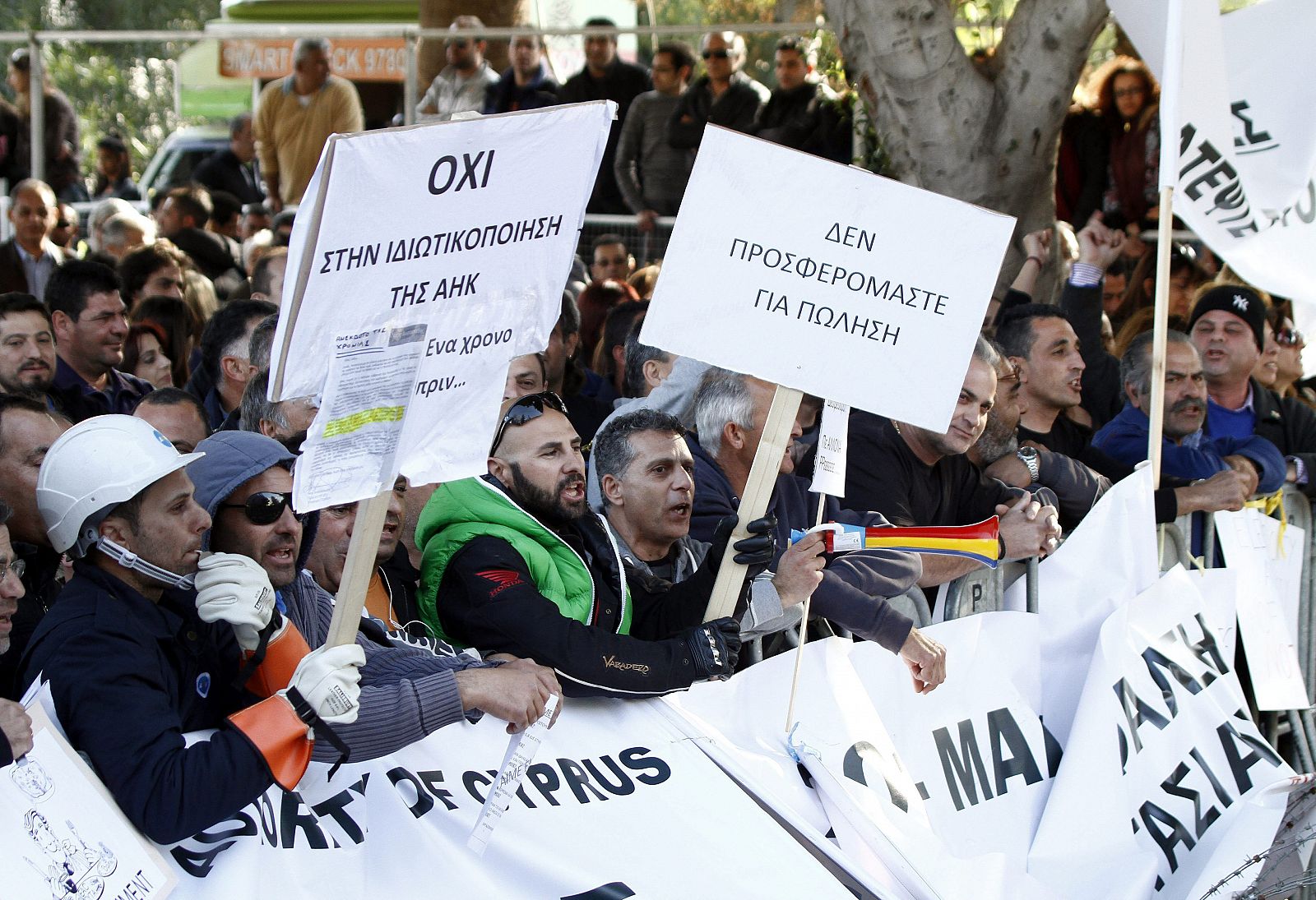 Empleados de la empresa eléctrica estatal chipriota muestran pancartas durante una manifestación contra la privatización de los entes públicos