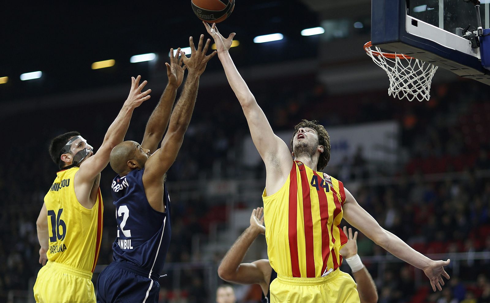 Los jugadores del Barcelona Ante Tomic (d) y Kostas Papanikolaou (i) pelean por el balón frente a Jamon Gordon (c) del Anadolu Efes