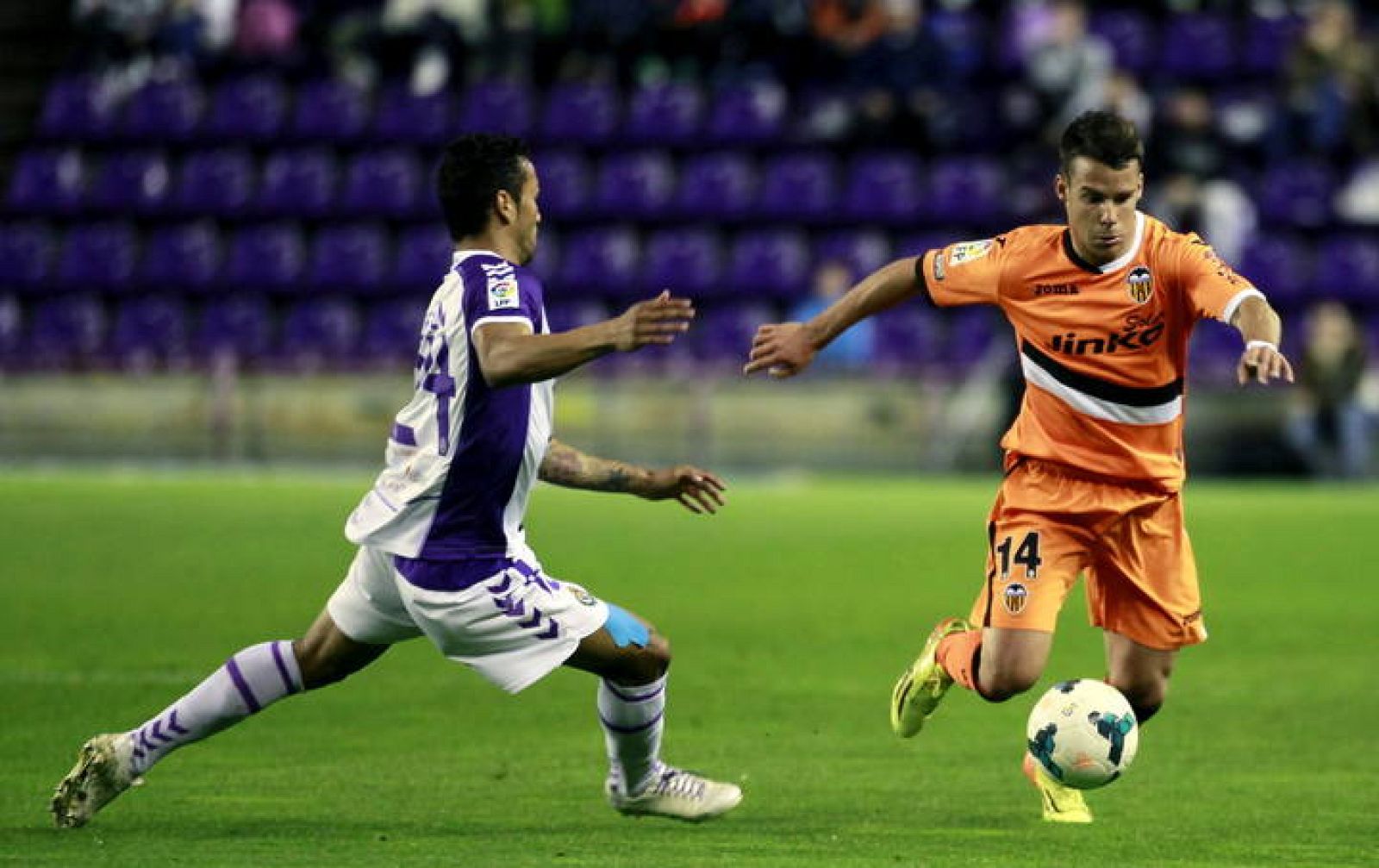 Juan Bernat (d) se lleva el balón ante Jeffrén Suárez (i) durante el partido.