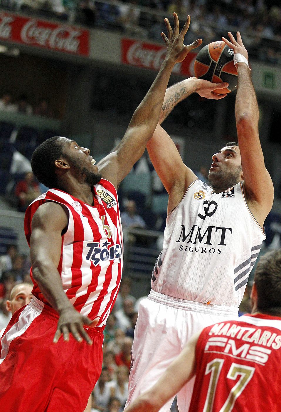 El pívot griego del Real Madrid Ioannis Bourousis (d) lanza a canasta ante el alero estadounidense del Olympiacos Bryant Dunston